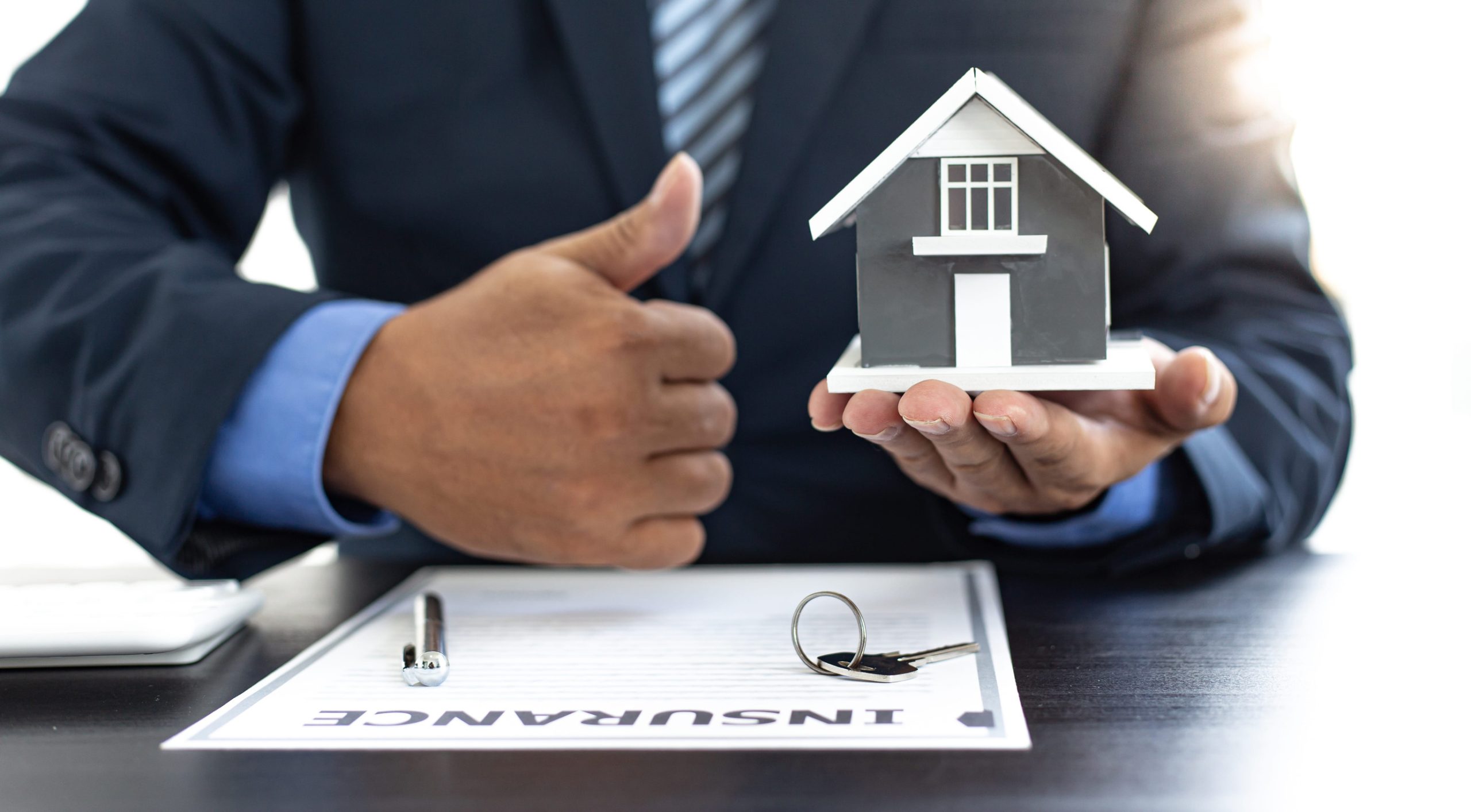 149817595_m Sales manager or real estate agent prepares to hand over the keys and the house together with the insurance to the customer